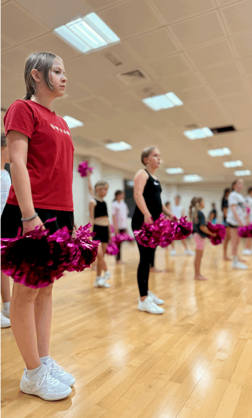 Girls practicing cheerleading indoors, focusing on teamwork, coordination, and energy as they perfect their stunts and routines in a well-lit practice space.